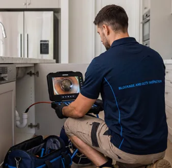 Plumber clearing a blocked toilet in a Miranda bathroom